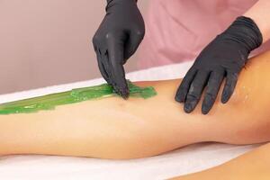 Waxing treatment on a clients leg at a beauty salon during a sunny afternoon session photo
