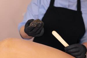 Waxing treatment being applied on a clients leg in a beauty salon during daylight hours photo