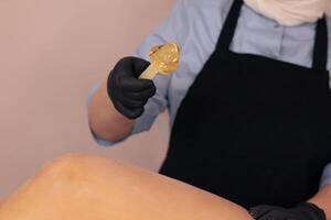 Waxing treatment being applied on a clients leg in a beauty salon during daylight hours photo