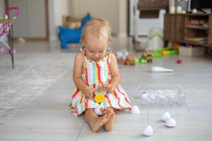 A beautiful blonde baby girl playing with a plastic montessori eggs photo