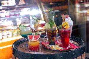 Colorful assortment of refreshing cocktails displayed on a rustic barrel outside a cafe in spring photo