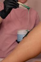 Waxing session in a beauty salon with green wax being applied to skin during treatment photo