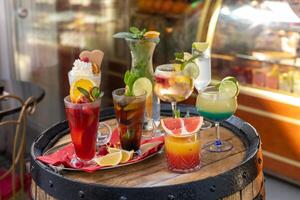 Colorful assortment of refreshing cocktails displayed on a rustic barrel outside a cafe in spring photo