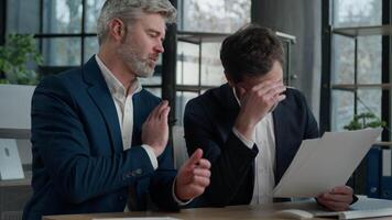 Two Caucasian men businessmen business partners argue in office meeting discussing bad project conflict failure failed contract mistake in financial papers illegal documents dissatisfied work result video