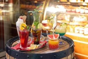 Colorful assortment of refreshing cocktails displayed on a rustic barrel outside a cafe in spring photo