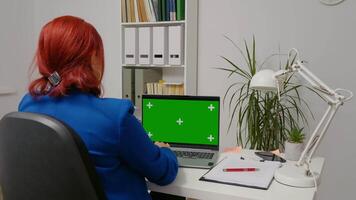 Business woman sitting working on laptop with mock up green screen display. video
