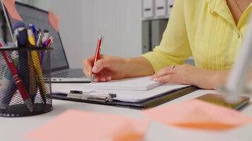 Close-up of woman hand taking notes of her new ideas working remotely video
