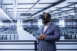 Engineer in data center implementing backup solutions to protect against data loss using VR headset, ensuring efficiency. Server room worker resolving technical issues using virtual reality tech photo