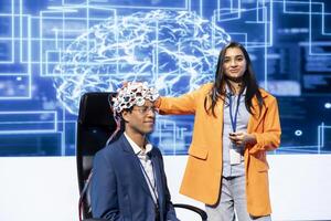 Smiling neuroscientists talking at AI convention, sharing neural implants industry insights to audience. Upbeat tech startup employees at tech event presenting latest AI EEG headsets photo