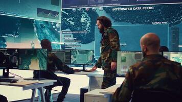 Staff sergeant providing mission files to brief his operational crew, working on gathering intelligence from surveillance systems. Prepares for various combat scenarios and outcomes. Camera B. photo