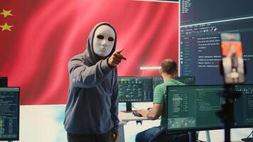Anonymous hacker expert in a Chinese hacking high tech office, digital threats and political espionage. Inflicting cyber terror, propaganda and crisis management in information war. Camera B. photo