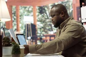 Professional entrepreneur examining blueprints and using digital tools for office space planning and development. Business owner focusing on workspace design for renting, investment strategy. photo