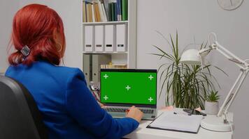 Freelancer sitting working on laptop with green screen chroma key display video