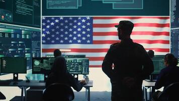 American military personnel ensuring servers protection and classified information, protecting state secrets in high tech agency office. Army soldier supervises hacking activity. Camera B. photo