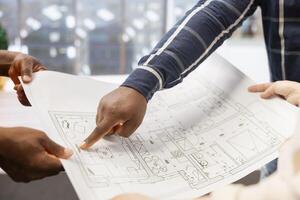 Business people examining blueprints and sketches with realtor during high class office space tour, discussing property layout. Negotiating contract for a modern workspace for relocation. photo
