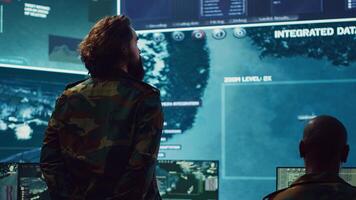 Sergeant major of the army handling a secret service operation by gathering intelligence from field troops and satellite CCTV imagery. Conducting a reconnaissance mission in command post. Camera A. photo