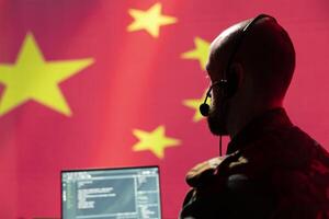 Chinese army telecommunication systems operator using radio and satellite gear, talking in headset mic. China military dispatcher managing communications networks, looking at notebook display screen photo