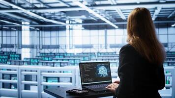 Engineer in data center using artificial intelligence computing simulating human brain thought processes in computerized model. Employee works on laptop with AI machine learning algorithms, camera B photo