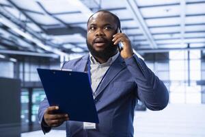 Manager maintaining accurate documentation of data center infrastructure, participating in phone call with employee. Expert talks about server hub configurations and procedures with worker photo