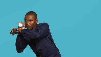 Security guard turning on flashlight and preparing baton to detect and detain suspects. Portrait of bodyguard using lantern and truncheon to subdue criminals, studio background, camera A photo
