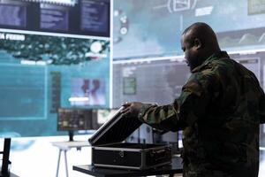 Army espionage specialist in a control center collecting satellite cctv data real time surveillance, supporting strategic military operations. Working to ensure national security and protocols. photo