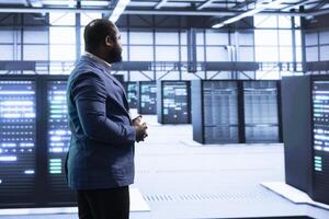 Technician walking in server hub, checking hardware after installing storage units. Skilled data center employee doing maintenance after replacing supercomputers components photo