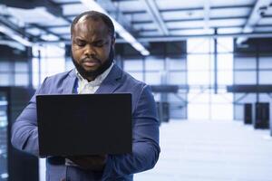 Engineer in server room using laptop to implement and maintain security measures, protecting systems from unauthorized access. Data center worker doing hardware installation using notebook photo