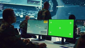 Female navy specialist monitoring warships activity along the national coast line, uses greenscreen to ensure protection. Woman IT operator working in power base command center. Camera B. photo