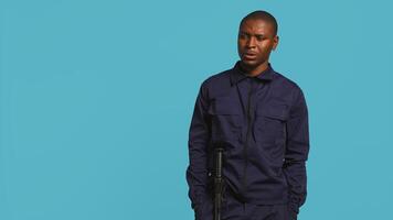 Portrait of security guard looking around while overseeing premises. Private law enforcement worker doing surveillance job, inspecting location, studio backdrop, camera B photo