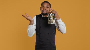 Waiter shrugging while he carries a cruet set with condiments, acting uncertain and showing i dont know symbol in studio. Professional customer focused staff is confused and unsure. Camera B. photo