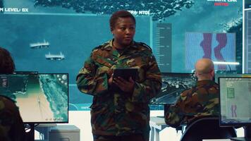 Female military officer supervising radar surveillance footage to input and process tactical data on a big screen. Woman uses global reconnaissance in creating battlefield maps. Camera A. photo