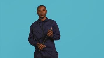 Portrait of security guard menacingly smacking hand with baton while overseeing premises. Private law enforcement worker cautioning trespassers with truncheon, studio backdrop, camera B photo