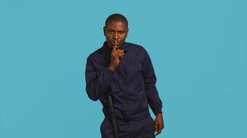 Portrait of security guard doing shush sign gesturing with finger to intruder while overseeing premises. Private law enforcement worker urging people to keep quiet, studio backdrop, camera B photo