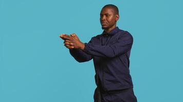 Portrait of security staff member tasked with evicting trespassers, pretending to shoot gun. Patrolling agent maintains secure environment, doing pistol fingers gesturing, studio background, camera B photo