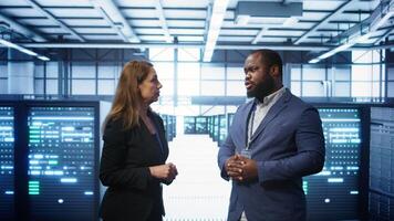 African american expert and coworker looking at holograms in data center, working together. Team members interacting with augmented reality AI visualization in server hub, camera B photo
