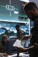Government intelligence officers in an operation room managing surveillance activity, gathering intelligence to help the troops. Analyzing real time data for national interests protection. photo