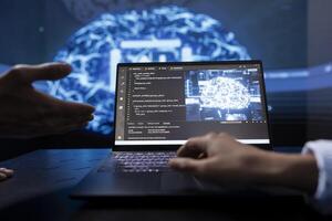 Technician and colleague use AI cognitive computing to extract information from complex data on laptop. Close up of teamworking IT experts using artificial intelligence on notebook photo