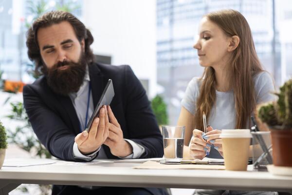 Financial advisor using tablet device to provide investing advice, guidance and stock recommendations to individuals. Agent in office helping his clients make sound investment decisions