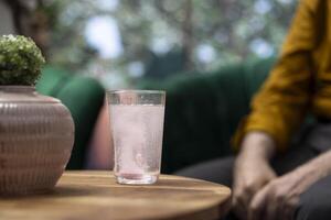 Elderly people drinking effervescent vitamins dissolved in water glasses, using for recovery and hydration. Senior couple taking supplements for wellness and longevity, health care. Close up. photo