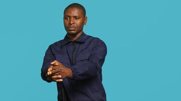 Portrait of security staff member tasked with evicting trespassers, pretending to shoot gun. Patrolling agent maintains secure environment, doing pistol fingers gesturing, studio background, camera A photo