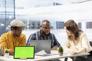 Contractors showing the office space plans next to tablet with chroma key, presenting the architectural blueprints to client. Business person looking to invest in property for development. photo