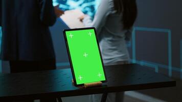 Green screen tablet used by computer scientists in startup doing advancements in AI field. Employees working on mockup device in workspace featuring artificial intelligence systems, camera A photo