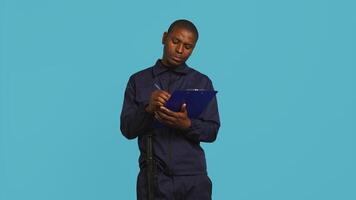 Security guard holding clipboard, taking notes, receiving orders during protection job shift. Portrait of bodyguard using pen to write informations received, studio background, camera B photo