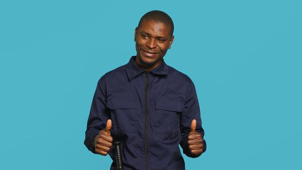 Happy security guard doing thumbs up sign gesturing with finger, preventing public access in restricted area. Portrait of smiling bodyguard doing positive hand gesture, studio background, camera A photo
