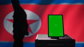 Mockup tablet used by North Korean state security services to coordinate terrorism attacks. Isolated screen device used by Pyongyang regime to control border, isolated over North Korea flag, camera B photo