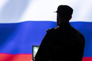 Ex KGB FSB secret police agent using mass propaganda technology tools on laptop to influence population minds. Russian spy silencing online opposition voices using notebook device photo