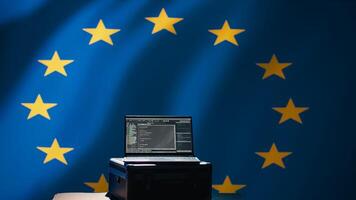 Laptop in European Union command center used by counterterrorism department to run security protocols against propaganda bots trying to destabilize democracy, isolated over EU flag, camera B photo