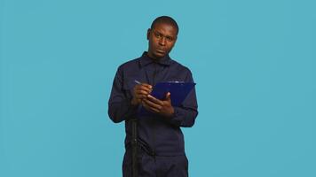 Portrait of security guard holding clipboard, taking notes while overseeing premises. Private law enforcement worker using pen to write down orders received, studio backdrop, camera B photo