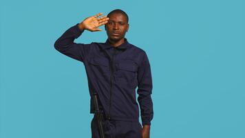 Security guard doing salute hand gesture, preparing to start job of deterring criminals. Portrait of bodyguard doing greeting gesturing and military pose, studio background, camera B photo
