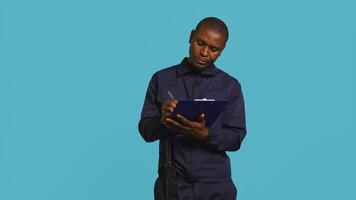 Portrait of security agent holding clipboard, taking notes, receiving orders to secure assigned post, studio background. Guardian maintains logs of observations, handling security breaches, camera B photo